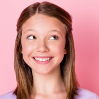 Insight Orthodontics - Young girl smiling in front of pink background